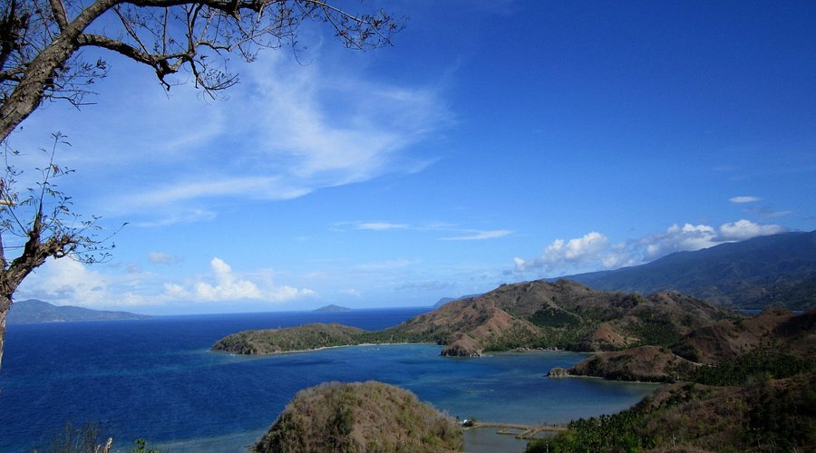 Scenic coastal view with blue ocean, islands, and mountains under a clear sky